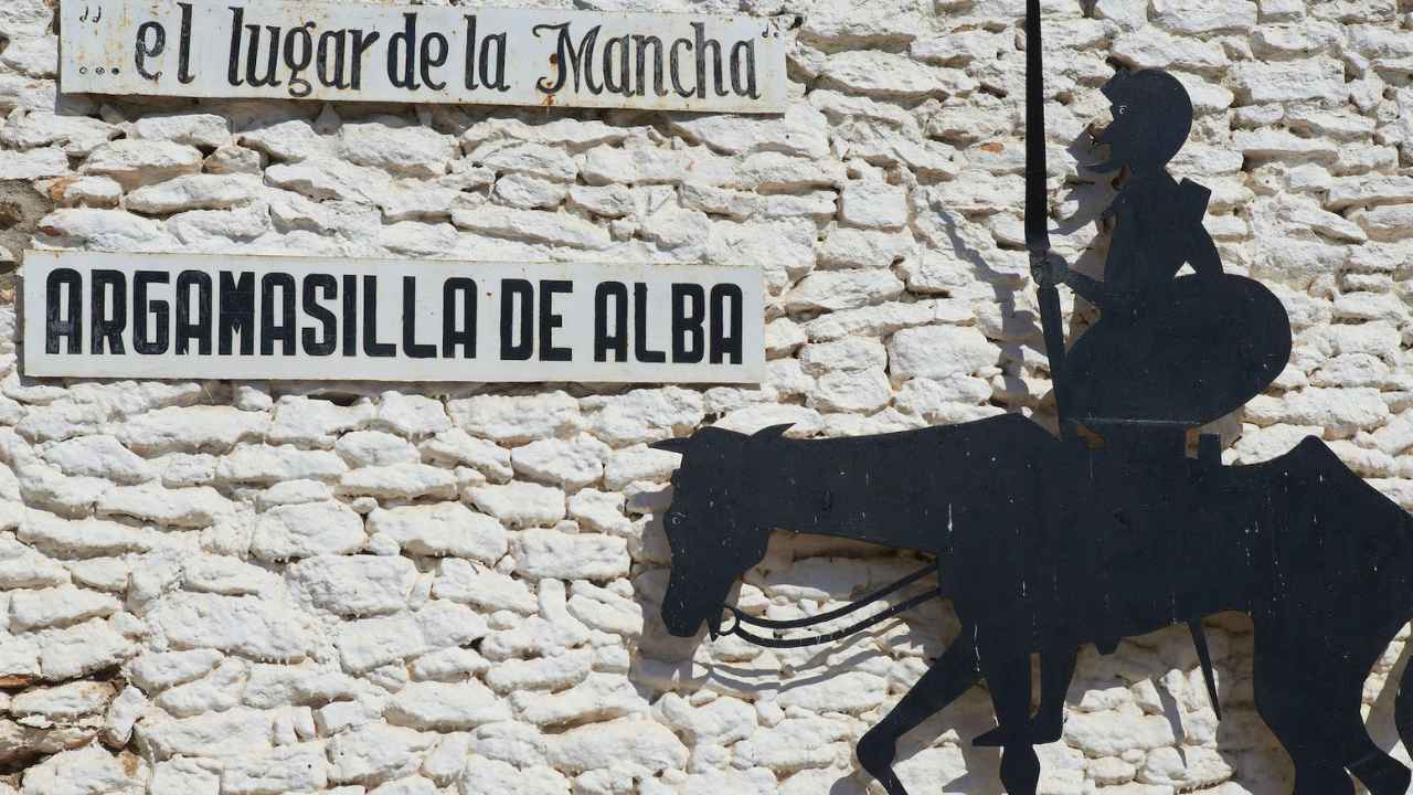 Cartel de Argamasilla de Alba junto a la figura de Don Quijote