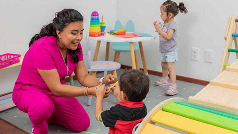 Profesional atendiendo a dos niños pequeños en un centro de cuidado infantil