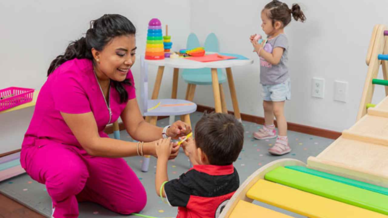 Profesional atendiendo a dos niños pequeños en un centro de cuidado infantil