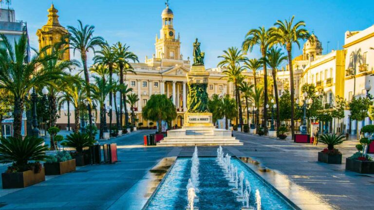Plaza de San Juan de Dios de Cádiz, con el monumento a Moret, palmeras y el Ayuntamiento de Cádiz al fondo.