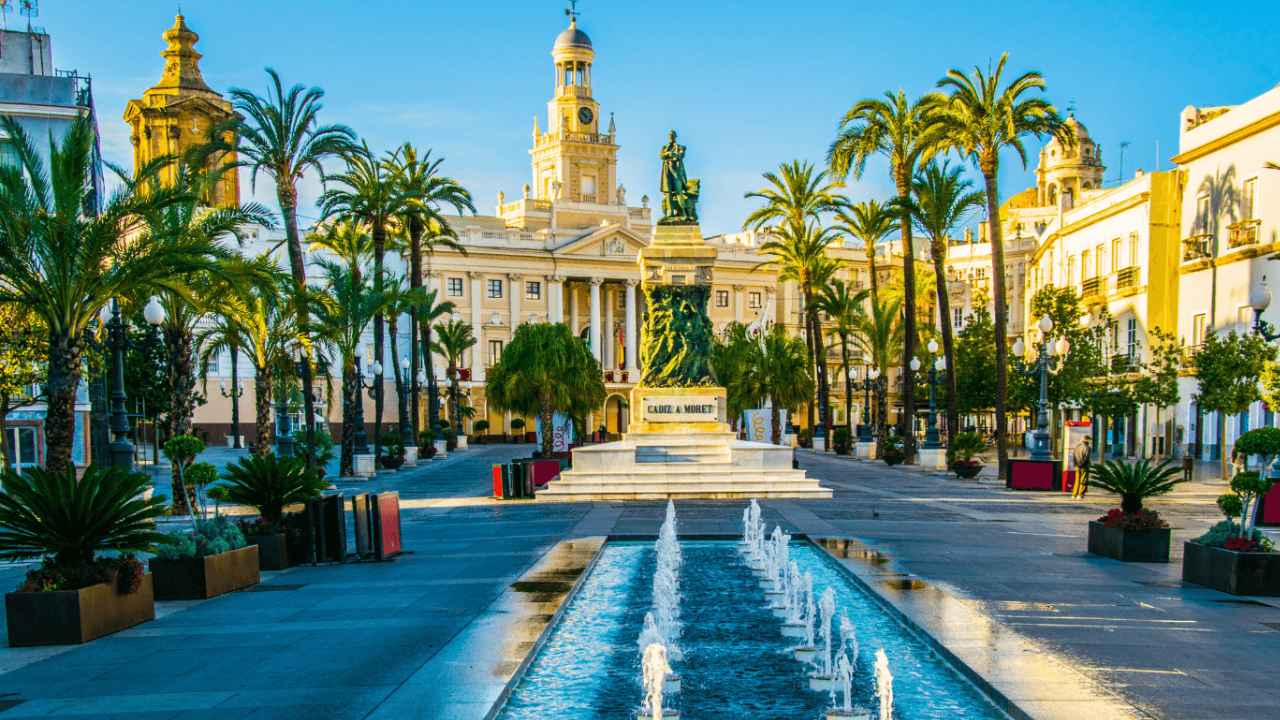 Plaza de San Juan de Dios de Cádiz, con el monumento a Moret, palmeras y el Ayuntamiento de Cádiz al fondo.