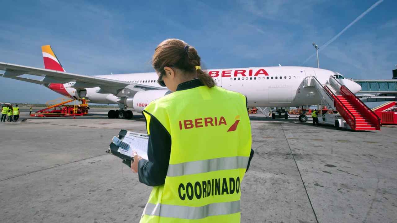 Trabajadora de Iberia junto a un avión de la compañía en un aeropuerto