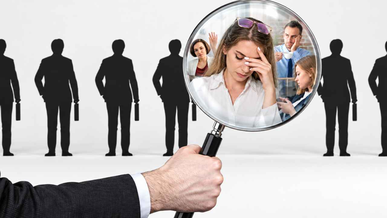 Lupa con imágenes de trabajadores ante una fila de siluetas, como ilustración del absentismo laboral.
