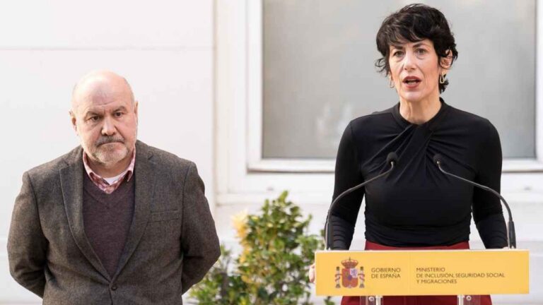 Elma Saiz interviniendo ante un atril del Ministerio de Inclusión, Seguridad Social y Migraciones, acompañada de un hombre.