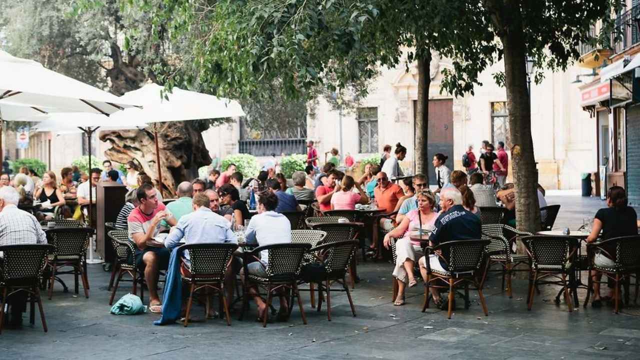 Terraza de hostelería llena de clientes y trabajadores atendiendo las mesas