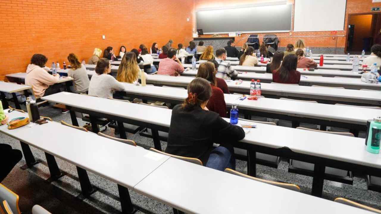 Personas sentadas en un aula con mesas dispuestas en filas.