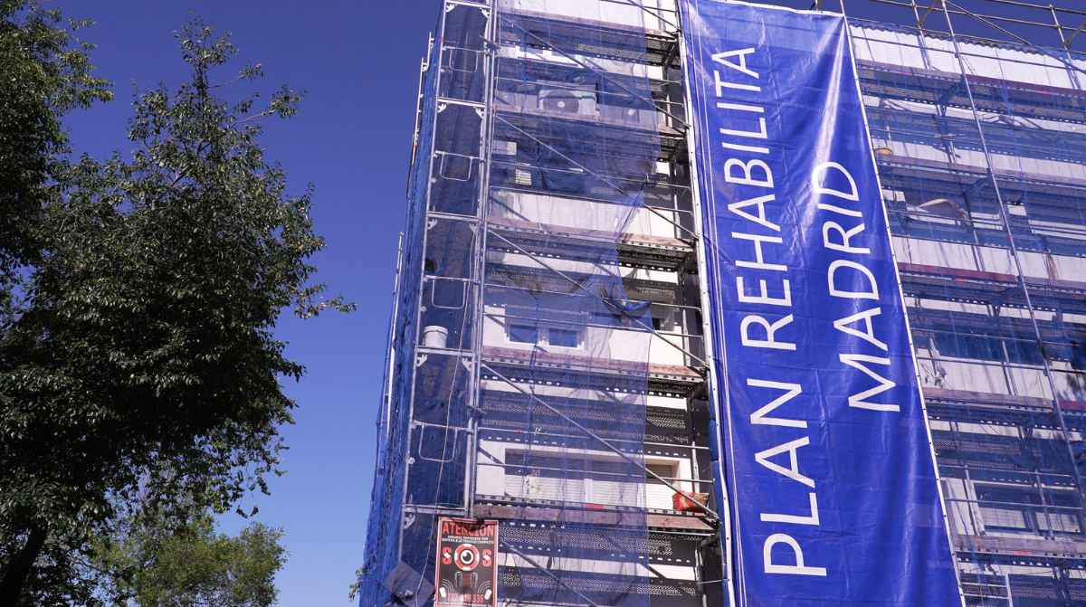 Edificio con andamios y una lona del Plan Rehabilita Madrid