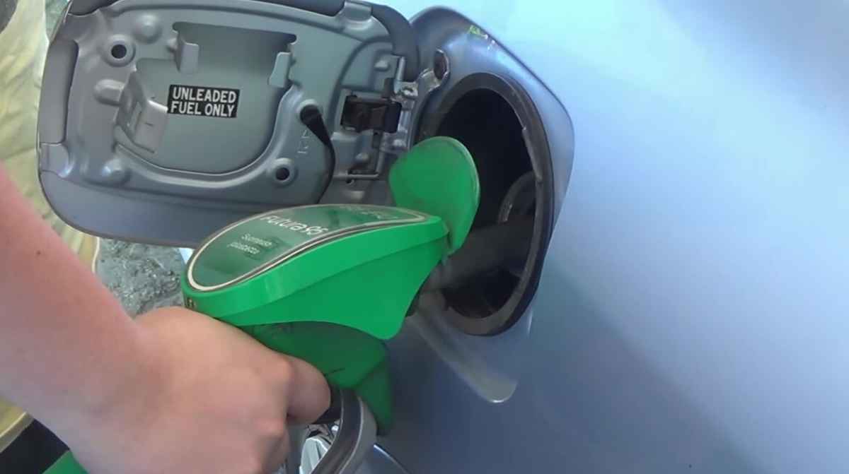 Boquilla verde de gasolina conectada al depósito de un automóvil durante el repostaje.