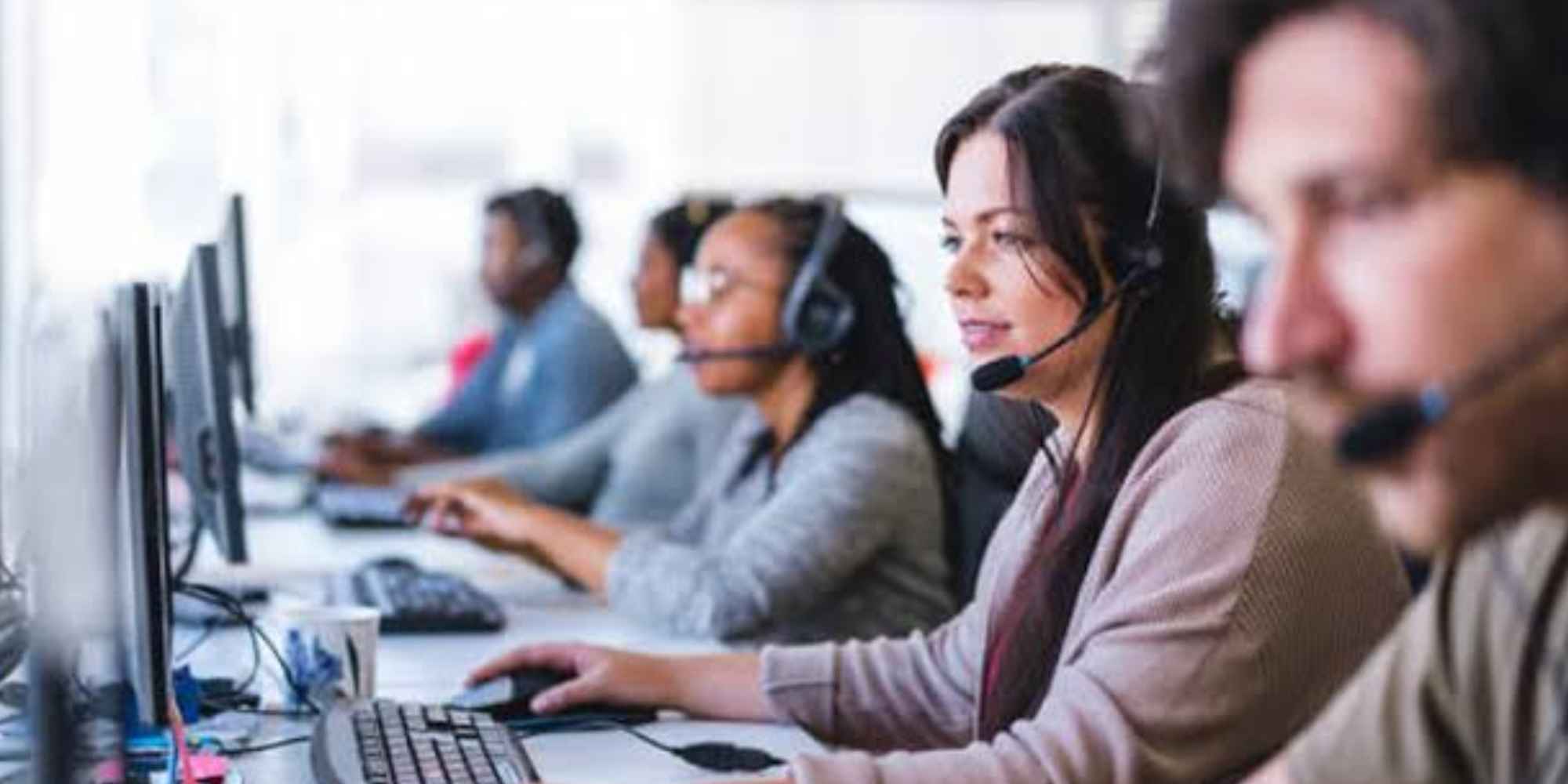Agentes telefónicos trabajando con auriculares en un centro de atención al cliente