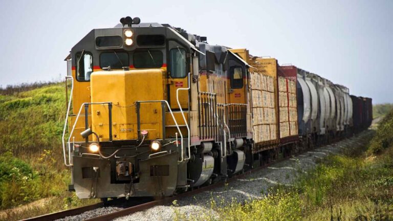 Tren de mercancías circulando por una vía ferroviaria con varios contenedores
