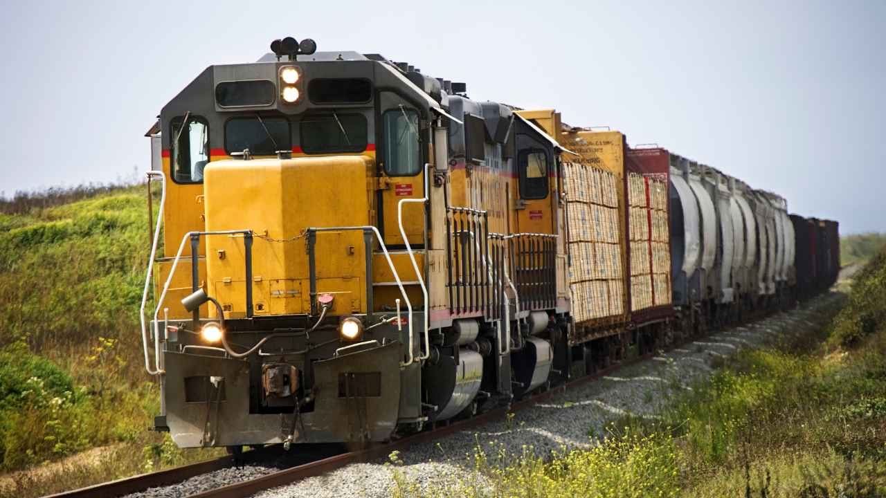 Tren de mercancías circulando por una vía ferroviaria con varios contenedores