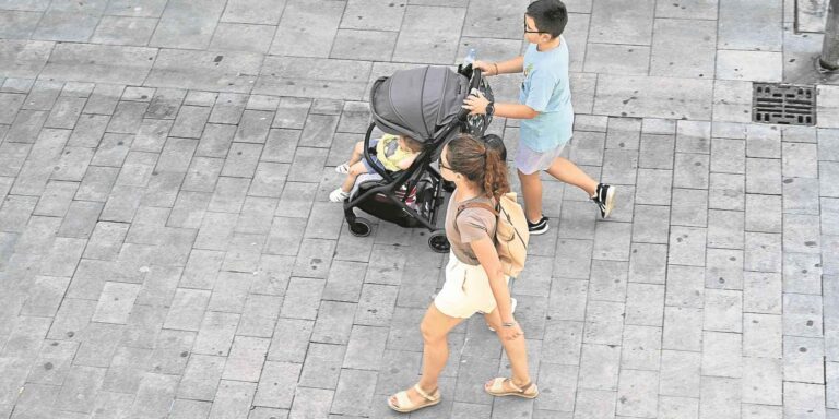 Familia paseando con un carrito de bebé por una calle, imagen ilustrativa de las ayudas familiares de hasta 2.500 euros en Murcia. Copiar