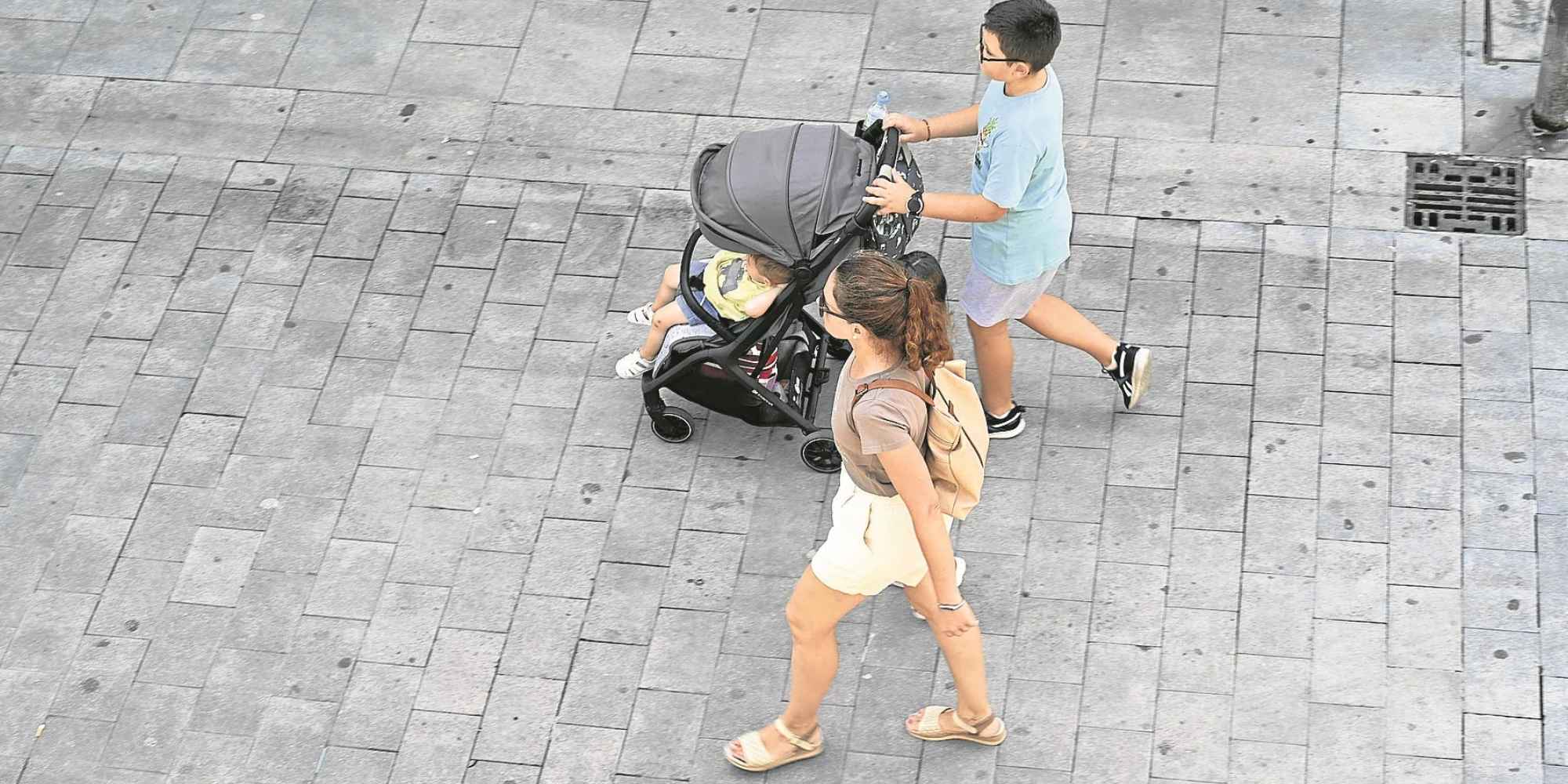 Familia paseando con un carrito de bebé por una calle, imagen ilustrativa de las ayudas familiares de hasta 2.500 euros en Murcia. Copiar