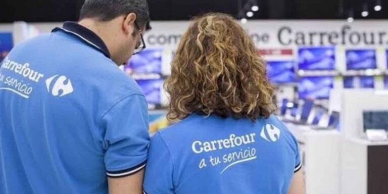 Dos empleados de Carrefour con uniforme azul trabajando en un establecimiento de la cadena de supermercados. Copiar