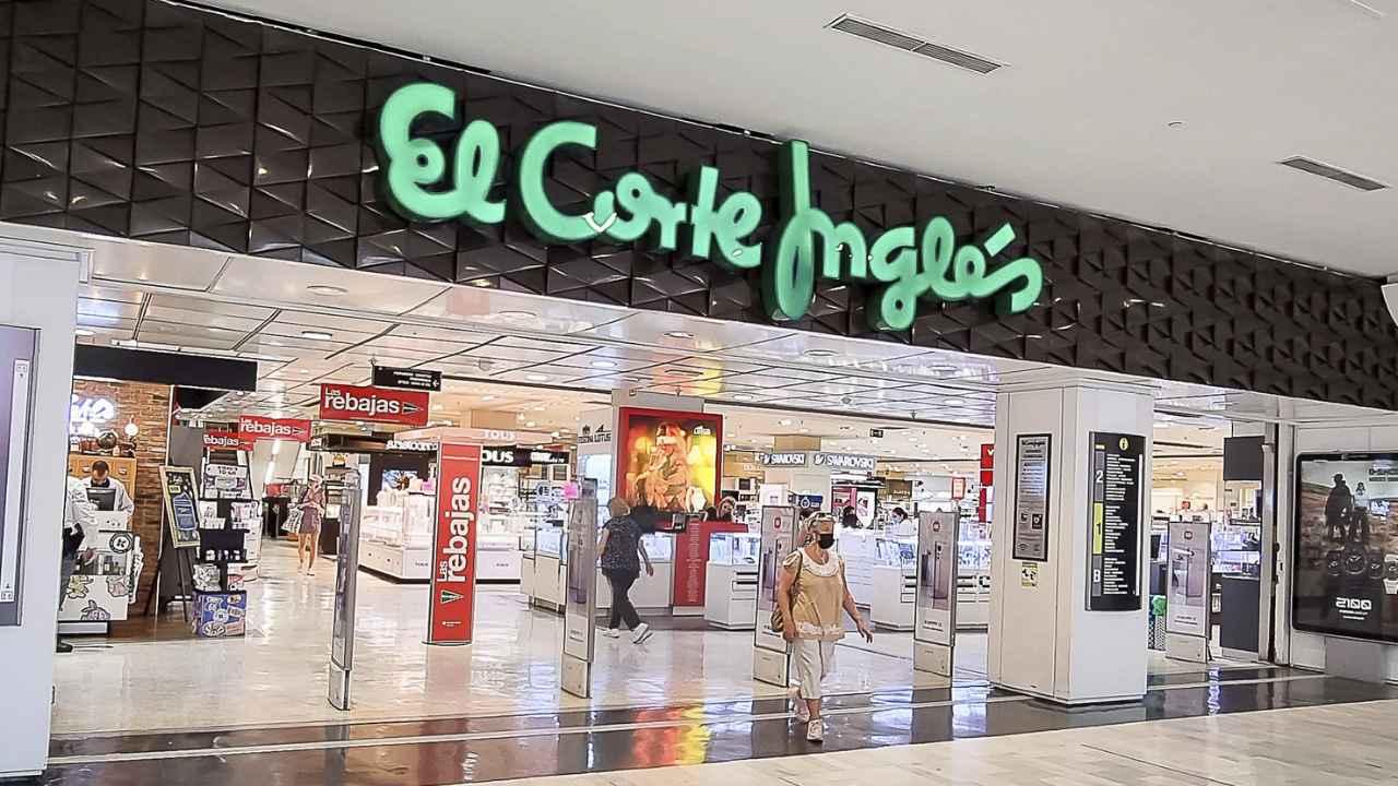 Entrada a un centro comercial de El Corte Inglés con el logotipo de la empresa y varios clientes en su interior.
