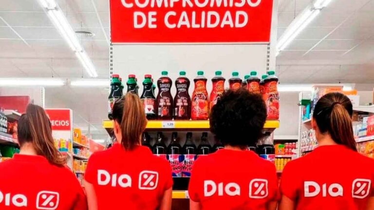 Cuatro trabajadoras de supermercados Dia con uniforme rojo, de espaldas, frente a una estantería de productos.