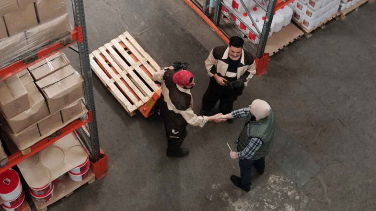 Trabajadores conversando entre estanterías y paquetes de un almacén.