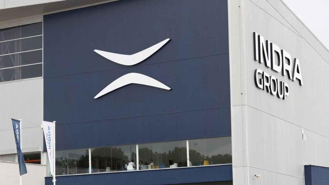 Dos personas trabajan frente a monitores con código informático en una oficina.
