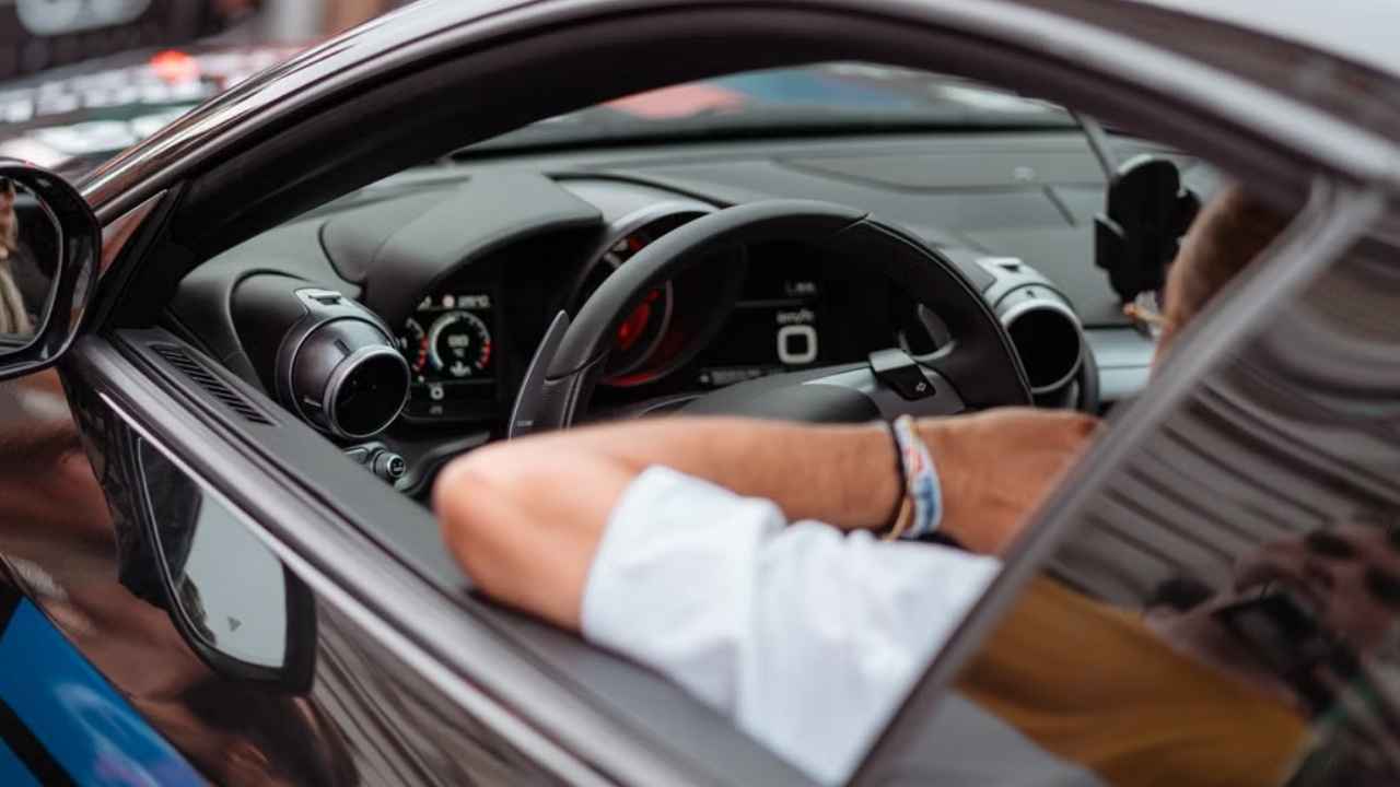 Conductor al volante de un automóvil, con el salpicadero visible.