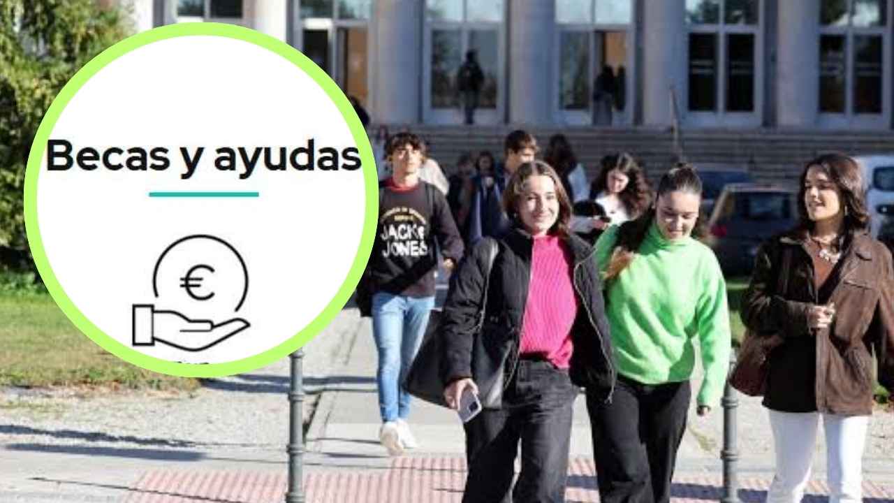 Estudiantes universitarios junto a un cartel de becas y ayudas por la convocatoria de 73 becas de 500 euros mensuales de la URJC.