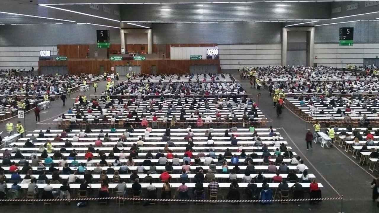 Centenares de aspirantes realizan un examen de oposiciones en un gran recinto habilitado para pruebas de empleo público.