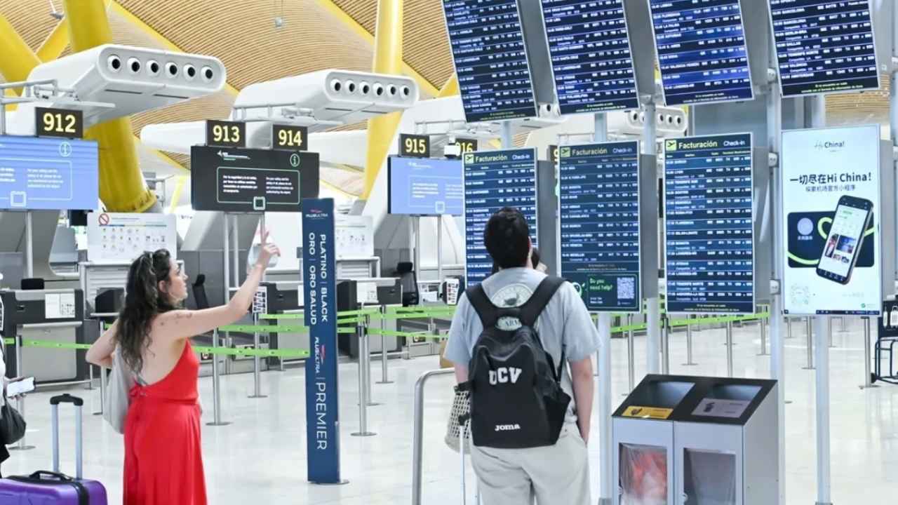 Viajeros consultan las pantallas de facturación de un aeropuerto ante los cambios en los derechos de los pasajeros aéreos en 2027.