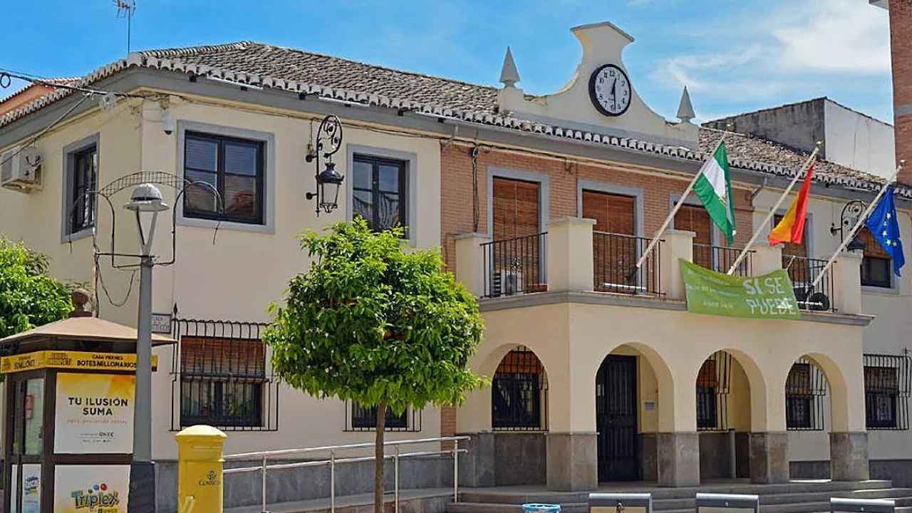 Fachada del Ayuntamiento de Peligros, en Granada, con las banderas oficiales y el reloj del edificio municipal.